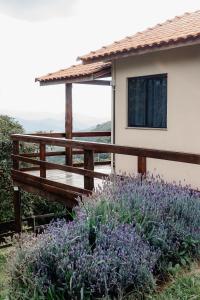 a house with a wooden deck and purple flowers at Chalé Romântico em Itamonte-MG in Itamonte +4 photos