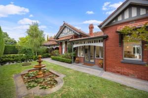 a brick house with a fountain in the yard at Complete Host Brighton House in Melbourne