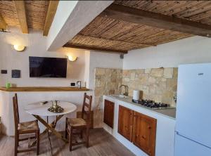 a kitchen with a table and a white refrigerator at Borgo Antico - Barrique Studio in Lotzorai