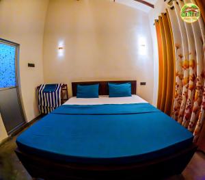 a bedroom with a large bed with blue sheets at Natura Villa in Hiriketiya