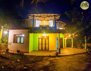 a small house with a green facade at night at Natura Villa in Hiriketiya