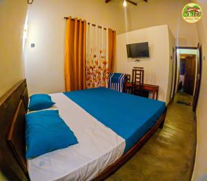 a bedroom with a large bed with blue sheets at Natura Villa in Hiriketiya