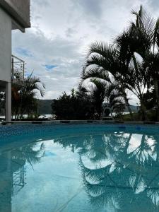 a blue swimming pool with palm trees in the background at Lago calima cabaña in Darién