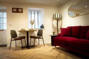 a living room with a red couch and a table at Coorie-In Cottage in Whitehills