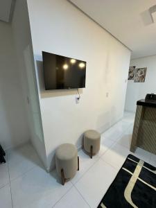 a room with two stools and a tv on a wall at Flat JK em Dona Inês-pb in Dona Inês