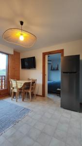 a kitchen and dining room with a table and a refrigerator at Chez Nathalie - Appartement cosy- Multi pass offert- Draps, serviettes et ménage compris in Saint-Jean-d'Aulps