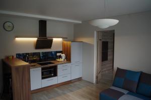 een keuken met witte kasten en een blauwe bank bij Jaukus butas Klaipėdos centre in Klaipėda