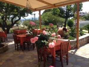a restaurant with tables and chairs and pink flowers at Vontzos Hotel in Achladies
