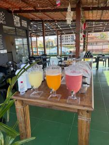 a table with four different colored drinks on it at Pousada do Francês in Ubatuba