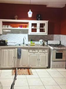 a kitchen with white cabinets and a sink at Tropical Tabago in Carnbee Village