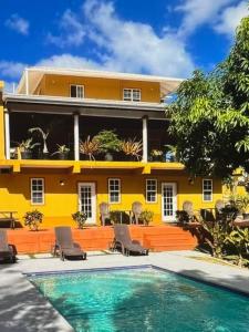 a yellow building with a swimming pool in front of it at Tropical Tabago in Carnbee Village