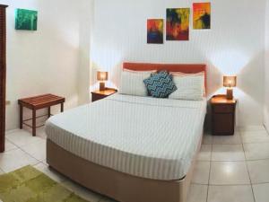 a bedroom with a bed with two night stands and two lamps at Tropical Tabago in Carnbee Village