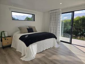 a bedroom with a bed and a large window at Pakawau Princess in Pakawau