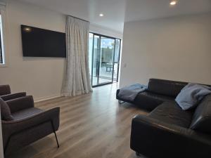a living room with a black couch and a tv at Pakawau Princess in Pakawau