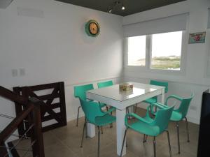 a dining room with a white table and green chairs at Linda Bay Playa in Mar de las Pampas