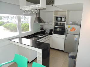 a kitchen with white cabinets and a black counter top at Linda Bay Playa in Mar de las Pampas
