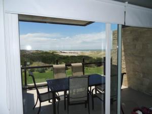 a table and chairs on a balcony with a view of the ocean at Linda Bay Playa in Mar de las Pampas