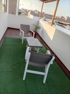 ein Balkon mit Tisch und Stühlen auf einem grünen Teppich in der Unterkunft Mary 2 in Paracas + 35 Fotos