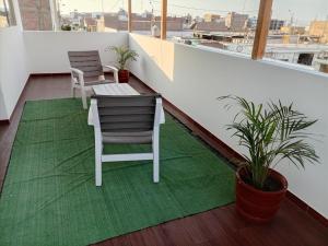 ein Balkon mit zwei Stühlen und einem grünen Teppich in der Unterkunft Mary 2 in Paracas