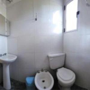 a bathroom with a white toilet and a sink at Yacaré INN in Ituzaingó