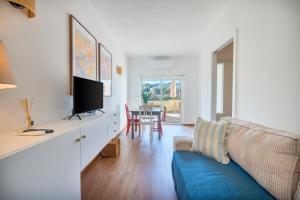 a living room with a blue couch and a tv at Ocean View - XL Terrace - Beachfront by Tenório in Lagos