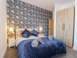 a bedroom with two beds with blue sheets and a floral wall at The Penthouse at 86 in Rossendale