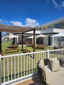 a balcony with a couch and tables and umbrellas at Praia dos Corais apt 79 in Santa Cruz Cabrália