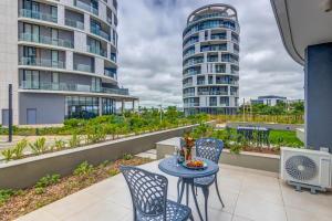 a balcony with a table and chairs and two tall buildings at Ellipse Soleya in Midrand