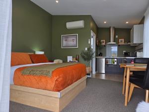 a bedroom with an orange bed and a kitchen at “No.25”Stand alone guest studio unit in Twizel