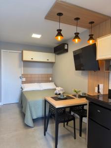 a bedroom with a bed and a table and a kitchen at Eco Green Container- Guarda do Embaú SC in Palhoça