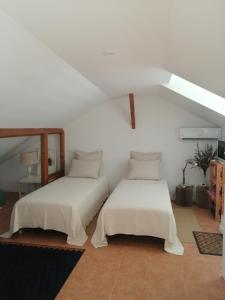 two beds in a room with white walls at A Casa da Vila in Alcochete