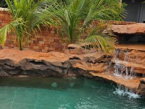 a swimming pool with a waterfall in a backyard at Aromas&Brumas Pousada in Brumadinho