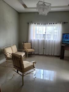 a living room with chairs and a television and a chandelier at Casa ampla e confortável in Corumbá