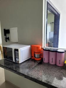 a kitchen counter with a microwave and four trash cans at Casa ampla e confortável in Corumbá
