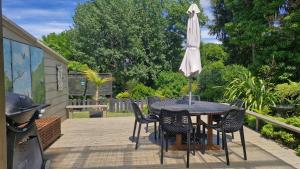 a table and chairs with an umbrella on a patio at Cheerful 3 bedroom villa in Gisborne