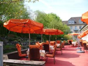 patio ze stołami i krzesłami z pomarańczowymi parasolami w obiekcie Campus Garden Businesshotel w mieście Iserlohn