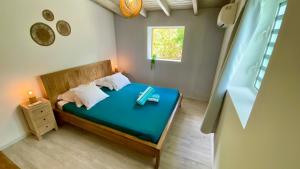a bedroom with a bed with blue sheets and a window at Grand Case Beach Steps in Grand Case