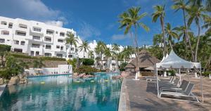 a pool at a resort with chairs and palm trees at Las Hadas by Brisas in Manzanillo