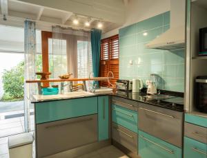 a kitchen with blue cabinets and a sink at Bungalow Brise Marine - Plaisir d Évasion in Deshaies