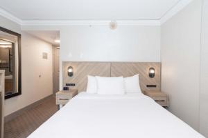 a bedroom with a large white bed with white pillows at Sandman Signature Vancouver Downtown Hotel in Vancouver