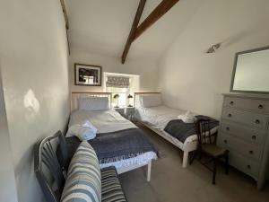 a bedroom with two beds and a dresser and a couch at 14 Boscaswell Downs in Lower Boscaswell