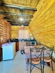 a kitchen with a table and two chairs and a refrigerator at Chale do Boni in Palhoça
