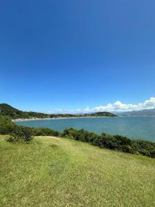a view of a body of water with a green field at Chale do Boni in Palhoça
