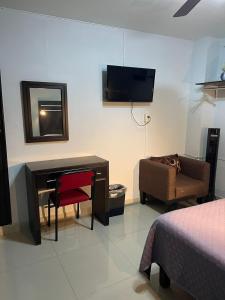 a room with a desk and a couch and a television at Camino de la Plata Hotel in Fresnillo de González Echeverría