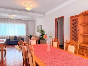 a dining room with a table and a living room at Apartamento Central em Araxá in Araxá