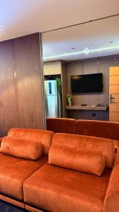 a brown couch sitting in a room with a refrigerator at Flat Vinhedo in Montes Claros