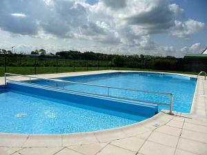 a large swimming pool with blue water in a field at Nieuwendamme H114 in Lombardsijde
