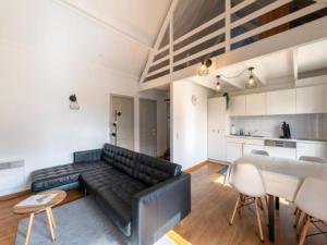 a living room with a black leather couch and a table at Nieuwendamme H114 in Lombardsijde