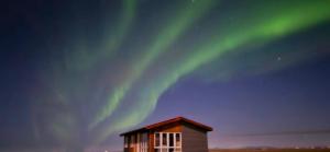 a building with the aurora in the sky at Vestra-Fíflholt 2 herbergja íbúð, fyrir allt að 8 gesti in Hvolsvöllur