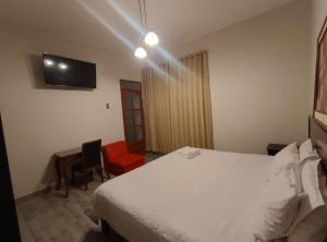 a bedroom with a bed and a desk and a tv at La Cabaña Hostal in Mollendo